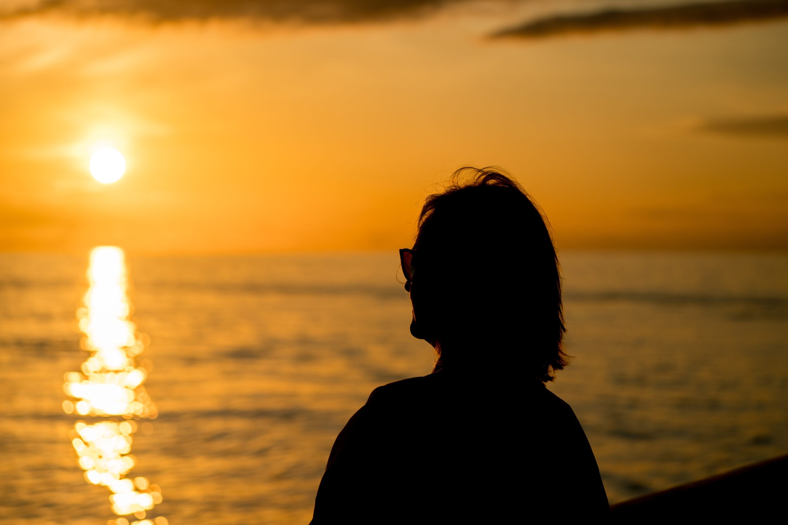 silhouette of woman standing facing sunset